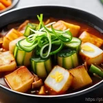 한국 떡볶이 종류별 소스 조합 - A close-up shot of a steaming bowl of Jjajang Tteokbokki in a cozy, softly lit home kitchen. The che...